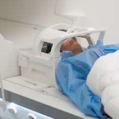 Pacjent leży w aparacie do rezonansu magnetycznego. Czas badania, czyli ile trwa rezonans głowy, zależy od wielu czynników.