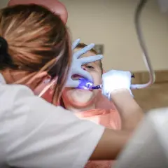 Dentysta z niebieskim światłem leczącym zęby dziecka.