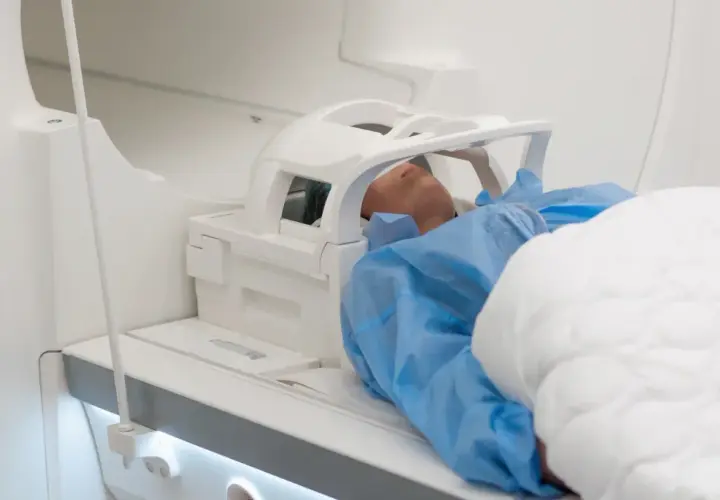 Pacjent leży w aparacie do rezonansu magnetycznego. Czas badania, czyli ile trwa rezonans głowy, zależy od wielu czynników.