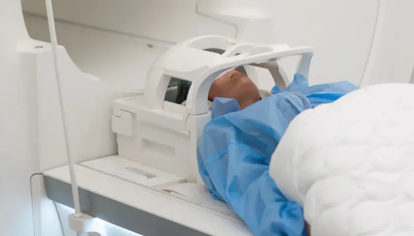 Pacjent leży w aparacie do rezonansu magnetycznego. Czas badania, czyli ile trwa rezonans głowy, zależy od wielu czynników.
