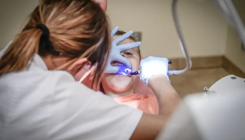 Dentysta z niebieskim światłem leczącym zęby dziecka.