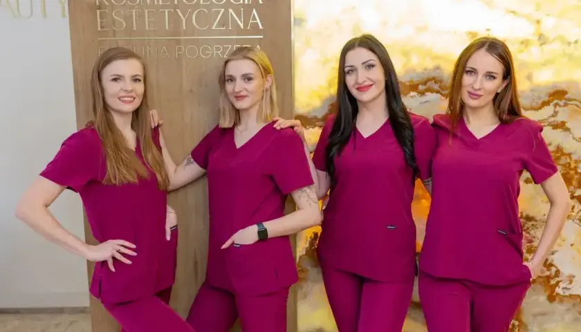 Cztery kobiety w uniformach medycznych stoją obok siebie, uśmiechając się do kamery.